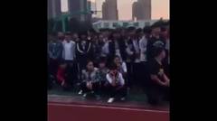para siswa di sebuah sekolah menengah di Henan, dipanggil ke sebuah majelis di lapangan atletik sekolah untuk melihat ponsel mereka dihancurkan